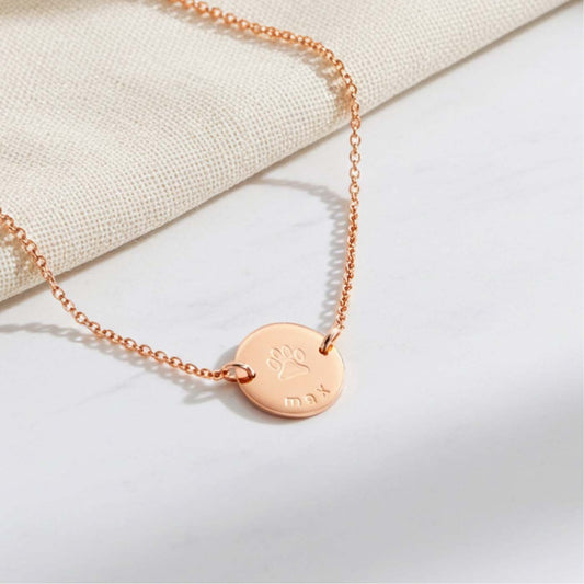 Rose gold necklace with a round pendant on a light background