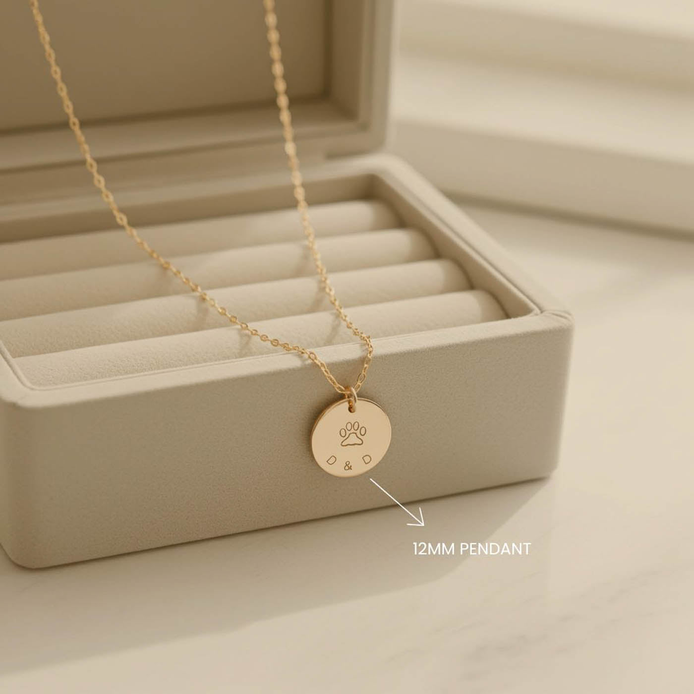 Gold necklace with a 12mm pendant on a beige jewelry display box.